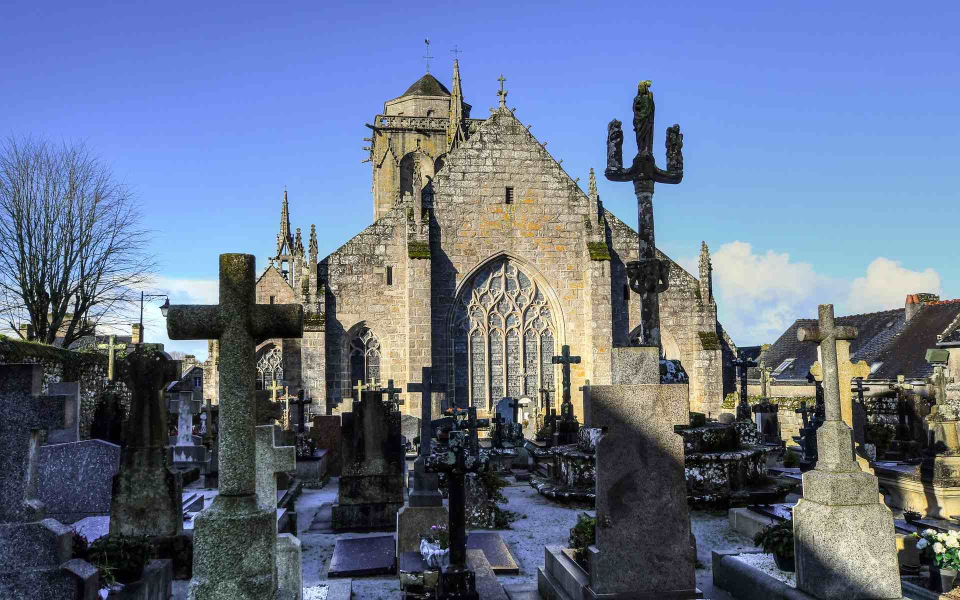 L’église Saint-Ronan et son cimetière. Au premier plan, les tombes formant le cimetière de Locronan. En arrière-plan, l’église Saint-Ronan dans la lumière du soleil. 