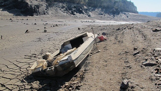 Le lac de Guerlédan vide, montrant un paysage lunaire. Un bateau est sur le sol, dépourvu d'eau sur laquelle flotter.