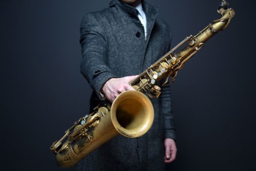 Un homme en costume portant un saxophone pour un festival de musique en Bretagne
