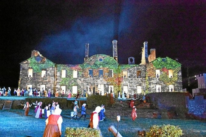 Photo prise de nuit de l'abbaye de Bon Repos pendant le spectacle Son et Lumière. Une foule de figurants costumés animent la reconstitution