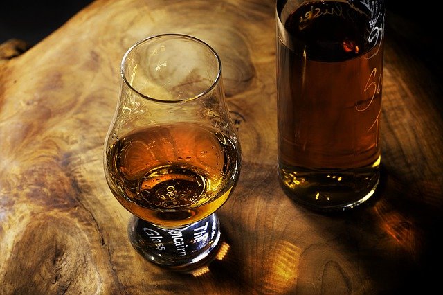 Verre de whisky breton sur une table en bois. La bouteille de whisky se tient sur le côté