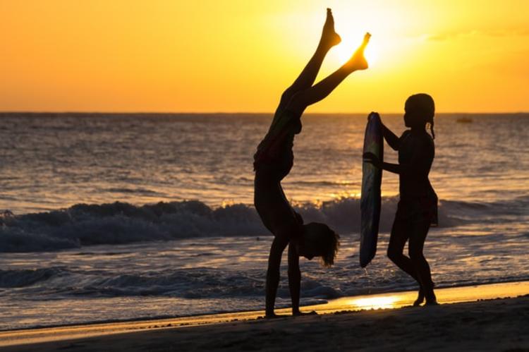 Enfants jouent au bord de la mer devant le coucher de soleil en Bretagne