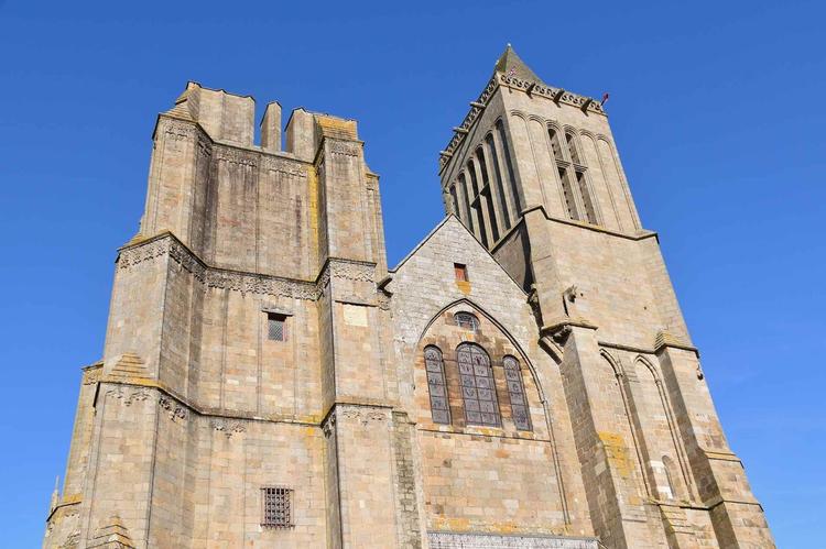 photographie en contre-plongé de la cathédrale Saint-Samson à Dol-de-Bretagne. Ciel bleu. Une des deux tours est absente.