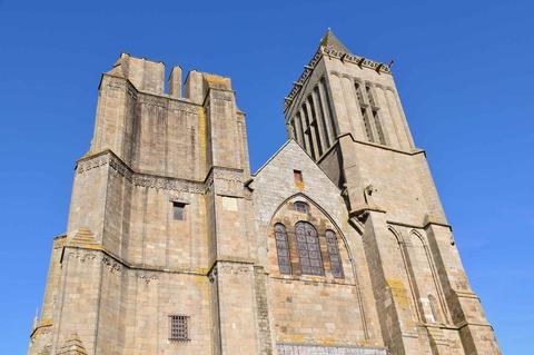 photographie en contre-plongé de la cathédrale Saint-Samson à Dol-de-Bretagne. Ciel bleu. Une des deux tours est absente.