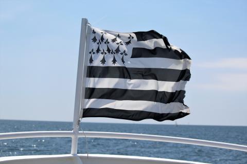 Le Gwenn ha Du, le drapeau breton blanc et noir, flotte au vent avec la mer en fond