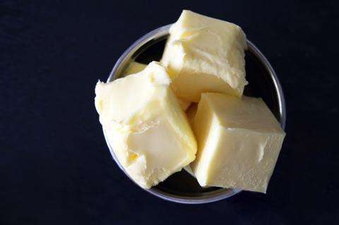 Trois morceaux de beurre salé breton dans un bol. Photo prise de haut avec un fond bleu marine