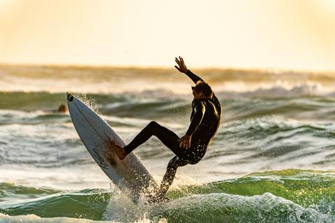 Un surfer sur une vague au coucher du soleil